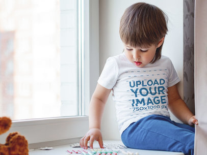 T-Shirt Mockup of a Kid Sitting by a Window 