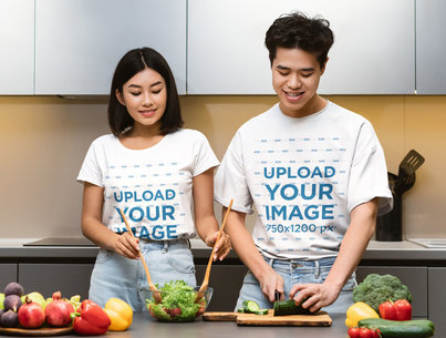T-Shirt Mockup of a Young Couple Preparing a Salad in a Kitchen