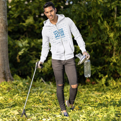 Mockup Featuring a Man Wearing a Full-Zip Hoodie While Cleaning a Park 