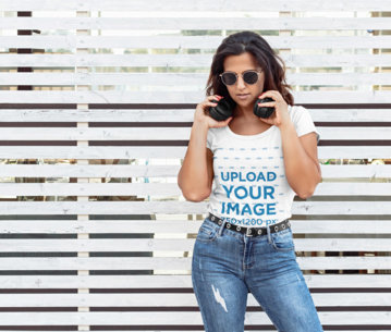 T-Shirt Mockup of a Woman With Headphones Posing in an Urban Setting