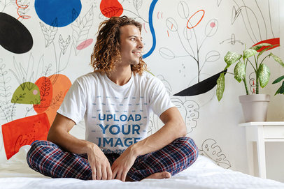 T-Shirt Mockup of a Long-Haired Man Sitting on His Bed 