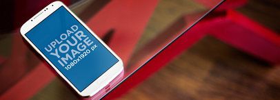 Mockup of a Samsung Galaxy in Portrait Position on a Glass Table