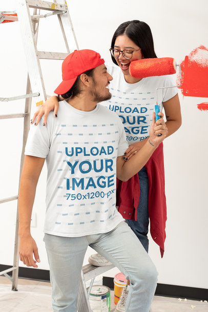 T-Shirt Mockup Featuring a Young Couple Painting Their Apartment's Wall 