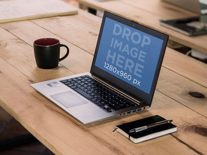 Mockup of a Laptop Placed Next to an Agenda on a Wooden Surface