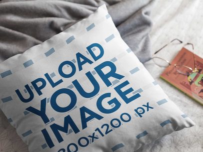 Mockup of a Pillow Lying on a Bed Near a Book