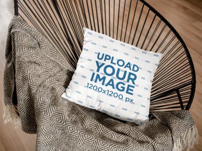 Mockup of a Pillow Lying on a Black Acapulco Chair in a Living Room