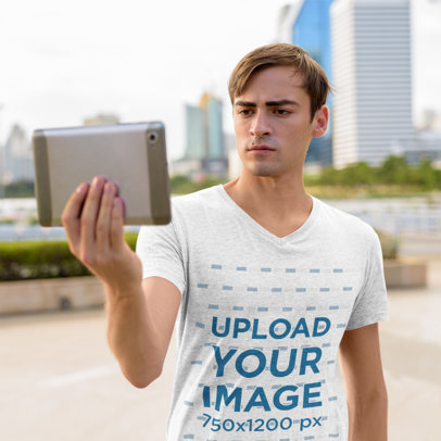 V-Neck Tee Mockup of a Serious Man Holding a Tablet 