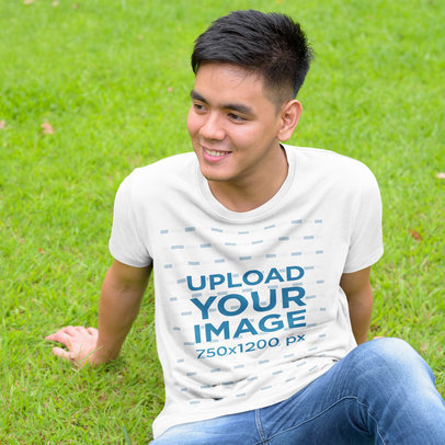 T-Shirt Mockup Featuring a Smiling Man Sitting on Grass 