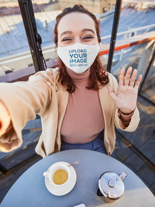 Face Mask Mockup of a Woman Taking a Selfie in a Coffee Shop