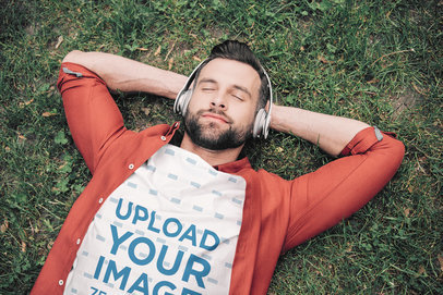 T-Shirt Mockup of a Relaxed Man Lying on the Grass with Headphones