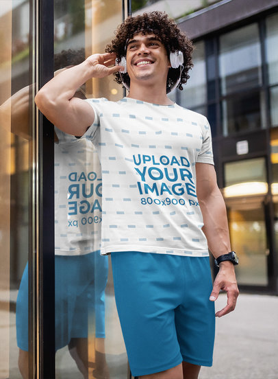 Sublimated T-Shirt Mockup of a Curly-Haired Man Listening to Music in the City 