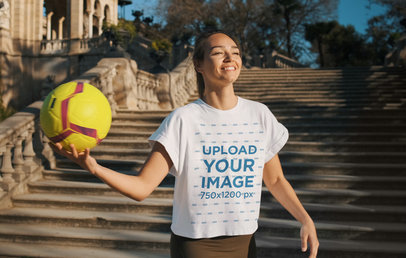 T-Shirt Mockup Featuring a Happy Woman Holding a Soccer Ball 