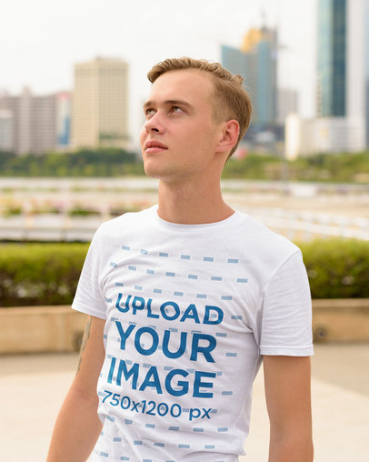 T-Shirt Mockup Featuring a Blonde Man in a City