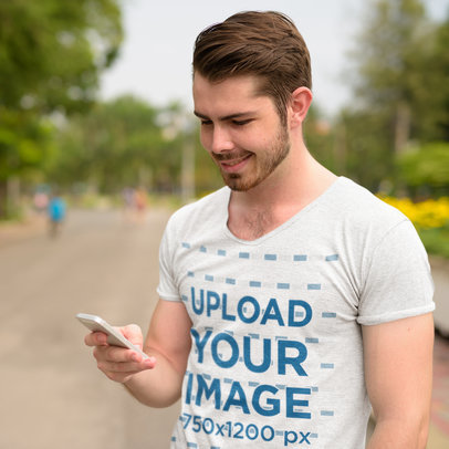 T-Shirt Mockup of a Man Checking His Phone on the Street