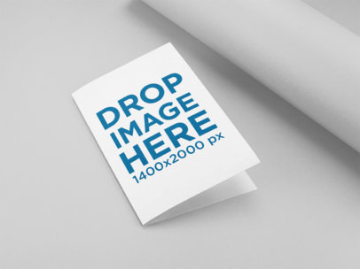 Mockup of a Bifold Brochure Lying Closed on a Solid Color Surface