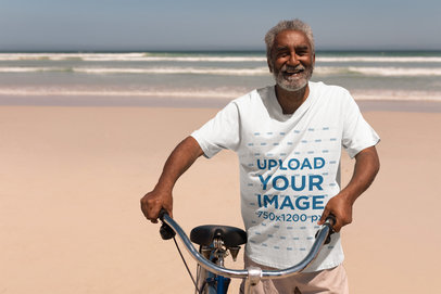 T-Shirt Mockup Featuring an Elderly Man with a Bike at the Beach