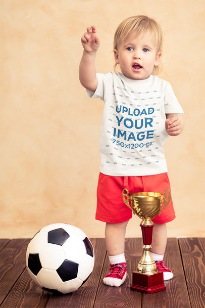 T-Shirt Mockup of a Little Boy with a Soccer Ball and a Trophy