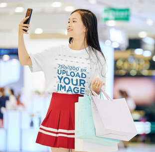 T-Shirt Mockup of a Woman Taking a Selfie While Shopping
