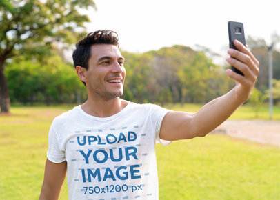 T-Shirt Mockup of a Smiling Man Taking a Selfie at a Park