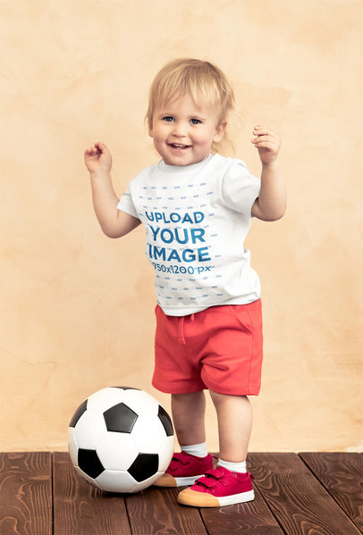 T-Shirt Mockup of a Toddler Standing by a Soccer Ball 