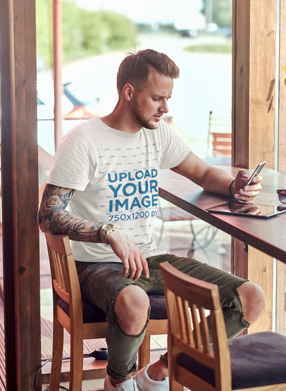 T-Shirt Mockup of a Man with a Tattooed Arm Checking Out His Phone 43451-r-el2