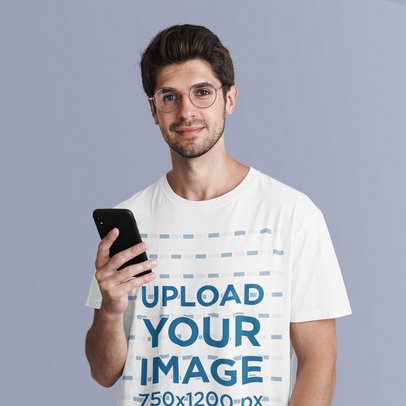 T-Shirt Mockup Featuring a Young Man Holding a Phone at a Studio