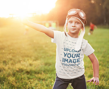 T-Shirt Mockup Featuring a Kid Playing With a Small Airplane Toy 