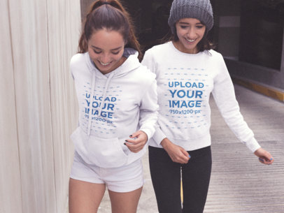 Mockup of Two Women Outside of a Tunnel Wearing a Pullover Hoodie and a Crewneck Sweatshirt