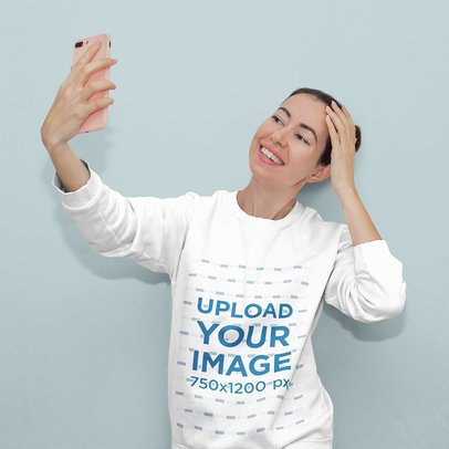 Sweatshirt Mockup Featuring a Woman Taking a Selfie in a Studio