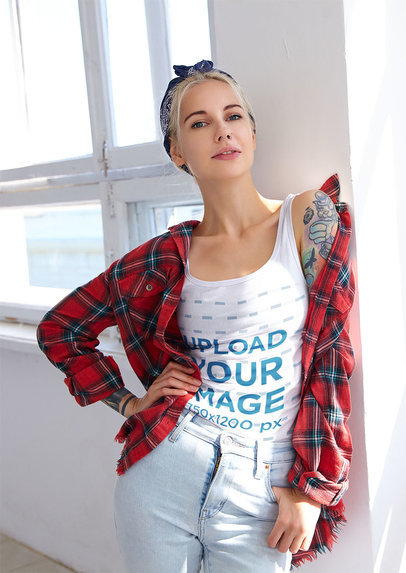 Mockup of a Tattooed Woman Wearing a Tank Top Mockup and Posing By a Window 