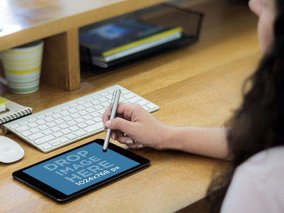 Mockup of a Woman Using an iPad Mini with a Stylus Pen