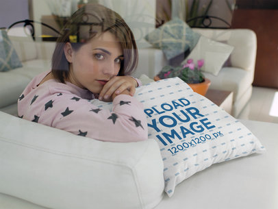 Young Woman Looking at the Camera While Lying Against a Square Pillow Mockup