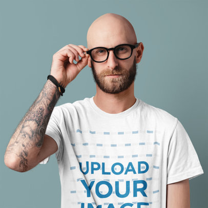 T-Shirt Mockup of a Man With Glasses and an Arm Tattoo at a Studio 
