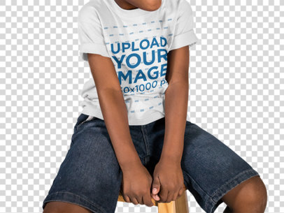 Child Wearing a Round Neck Tee Mockup Sitting on a Wooden Stool While Against a Transparent Backdrop