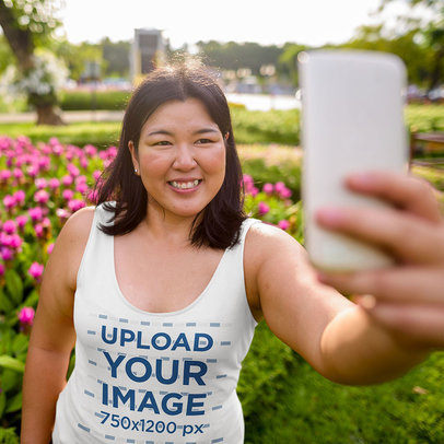 Tank Top Mockup Featuring a Smiling Woman Taking a Selfie at a Garden