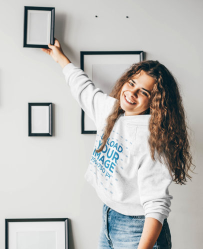 Hoodie Mockup of a Curly-Haired Woman Decorating a Wall 