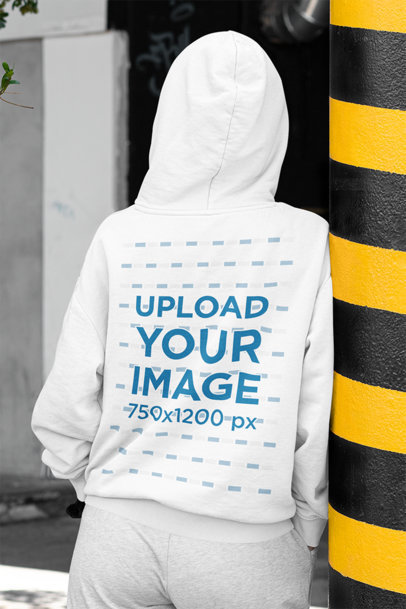 Mockup of the Back of a Woman Wearing a Hoodie in the Street