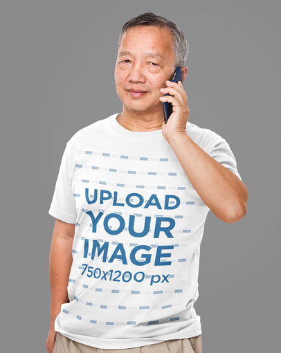 T-Shirt Mockup of a Senior Man Talking on His Mobile Phone at a Studio