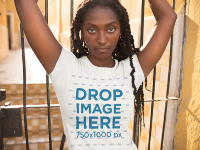 Mockup of a Young Woman Wearing a Round Neck T-Shirt Standing in a Yellow Building 