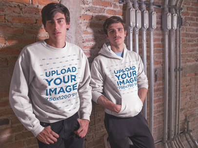 Two White Guys Wearing Different Designs on a Crewneck Sweatshirt and a Pullover Hoodie Template Whlie Lying Against a Bricks Wall