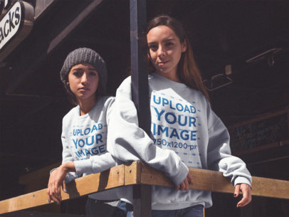 Two Girlfriends Hanging Out and Wearing Different Crewneck Sweatshirts Mockup at a Bar Terrace