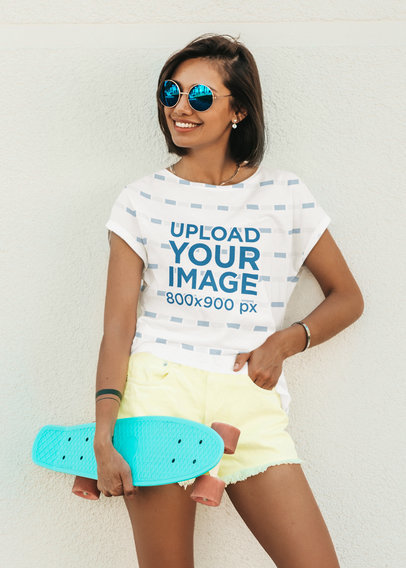 Sublimated T-Shirt Mockup of a Young Woman Holding a Small Skateboard 