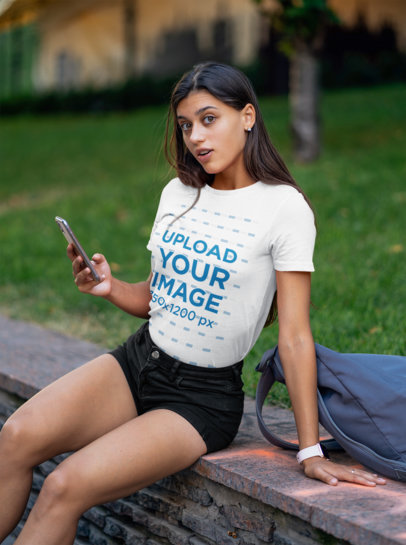 T-Shirt Mockup of a Woman Using Her Mobile Phone