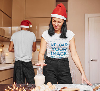 Christmas-Themed Mockup of a Woman Wearing a Round-Neck Tee and a Santa Hat While Cooking m2150 r-el2