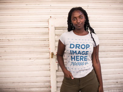 Mockup of a Young Woman Wearing a Round Neck T-shirt While Standing Against a White Urban Background 