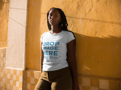 Young Woman Wearing a Round Neck Tee Template While Lying Against a Yellow Wall