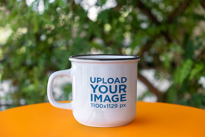 Mockup of a 12 oz Enamel Coffee Mug Placed in an Outdoor Setting
