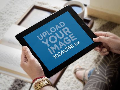 Mockup of a Black iPad Being Held Inside a Living Room