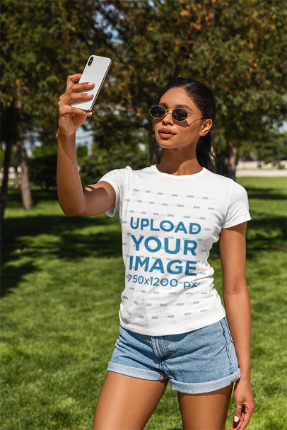 T-Shirt Mockup of a Woman Taking a Selfie at a Park