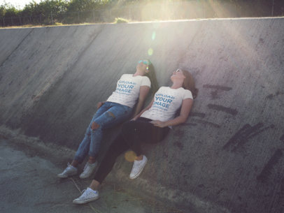 Two Women Lying Down While at an Industrial Area Wearing Different T-Shirts Mockup